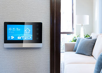 A smart thermostat positioned on a wall overlooking a modern style living room